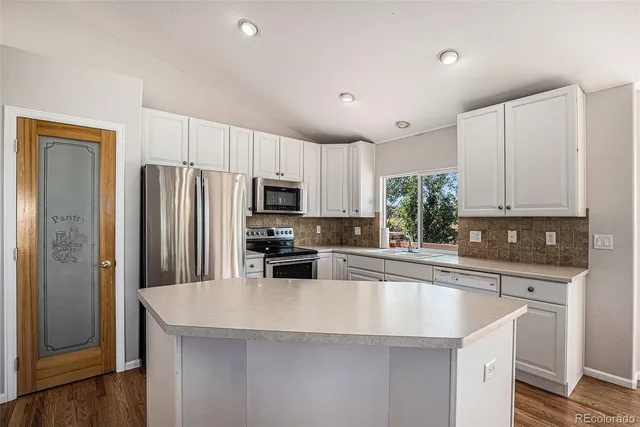 a kitchen with granite countertop a refrigerator a sink a stove a microwave and island