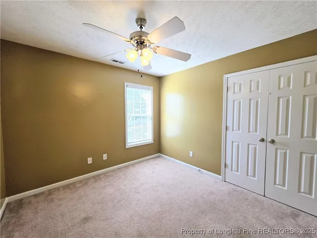 an empty room with a window and a fan