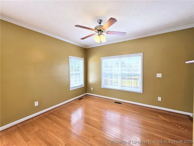 a view of an empty room with window and wooden floor