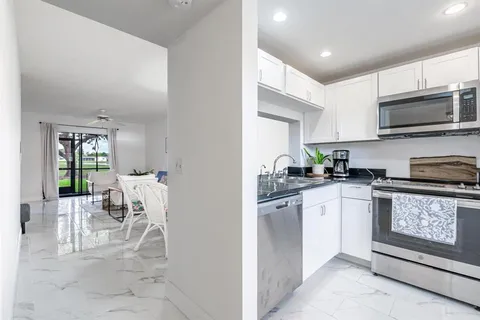 a kitchen with stainless steel appliances granite countertop a stove top oven a sink a dining table and chairs