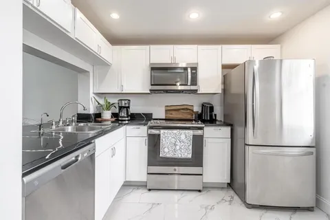 a kitchen with stainless steel appliances granite countertop a refrigerator sink and microwave