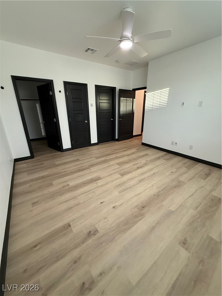 7368 North Decatur Boulevard, Unit 1 North Las Vegas, NV 89084 - Photo 11 of 17 Unfurnished bedroom with two closets, a ceiling fan, and light wood finished floors