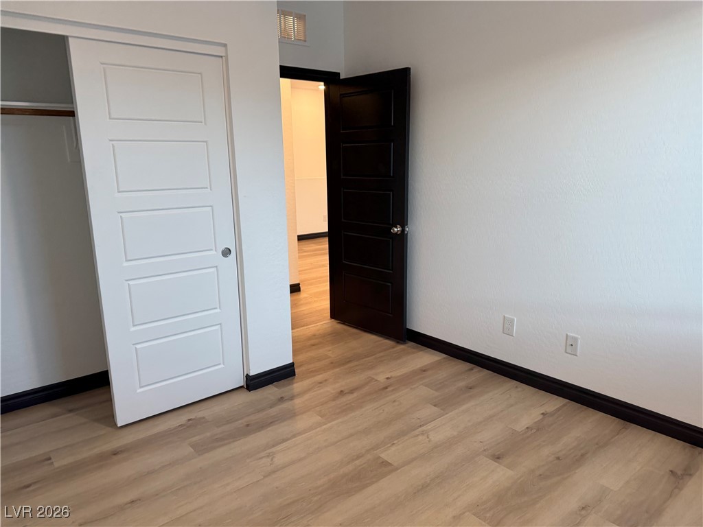 7368 North Decatur Boulevard, Unit 1 North Las Vegas, NV 89084 - Photo 5 of 17 Unfurnished bedroom featuring light wood-style floors and a closet