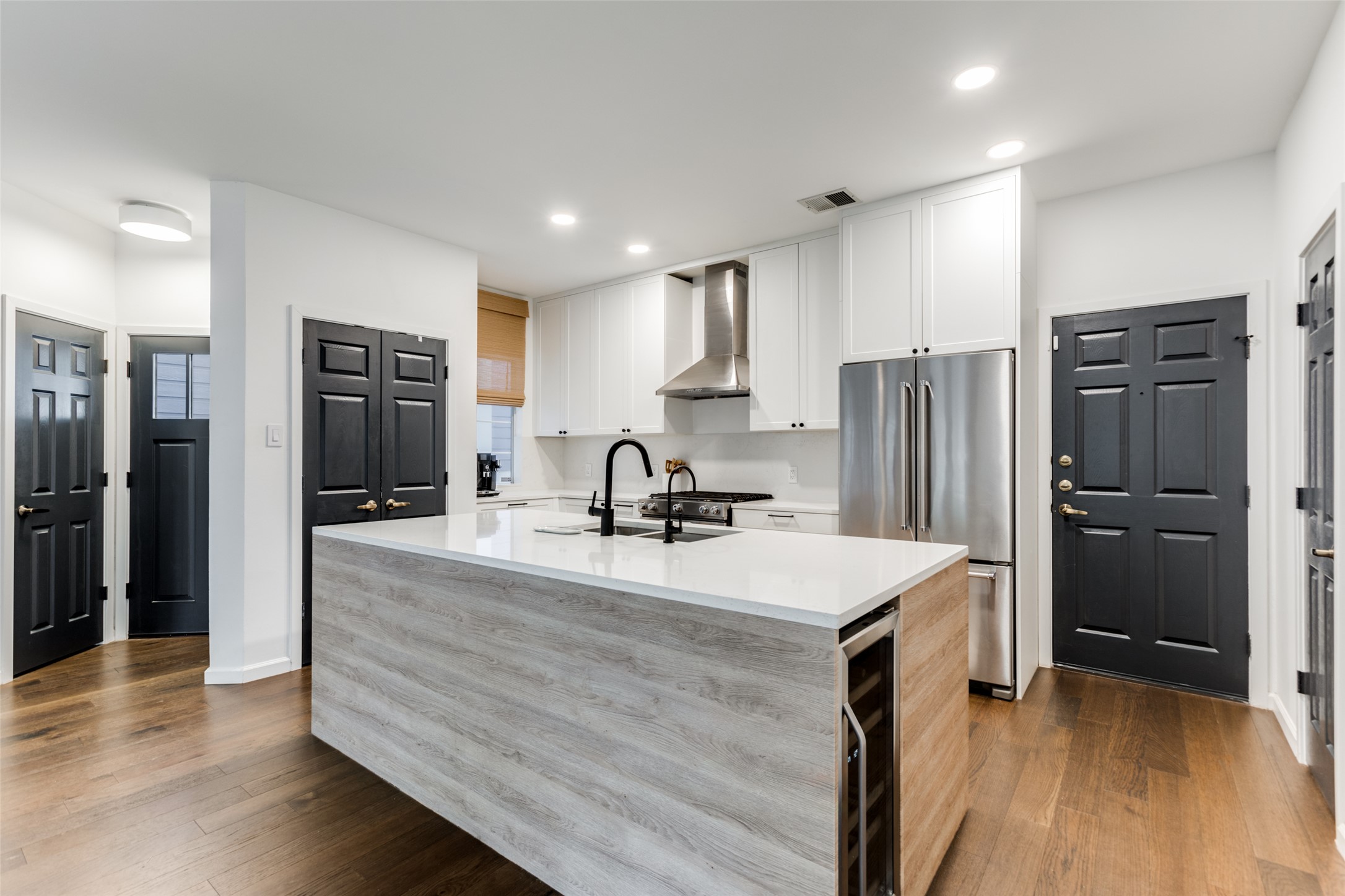 411 West St Elmo Road, Unit 35 Austin, TX 78745 - Photo 10 of 21 Two tone kitchen featuring high end refrigerator, an island with sink, dark wood-style flooring, two tone cabinetry, and light stone countertops