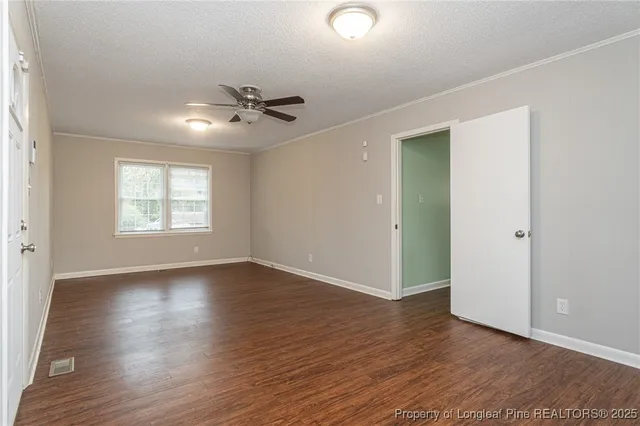 an empty room with wooden floor chandelier fan and windows