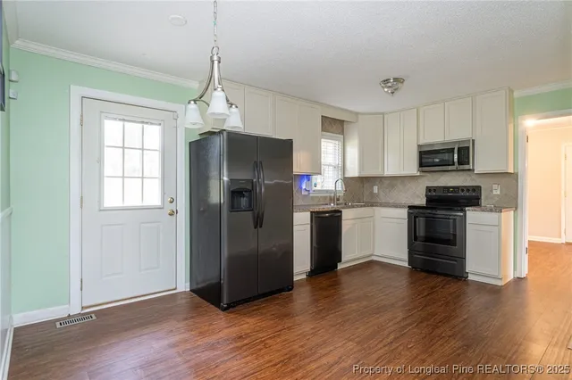 a kitchen with granite countertop a refrigerator a sink dishwasher a kitchen island with wooden floor and cabinets