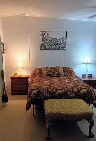 a bedroom with a bed and a lamp on dresser