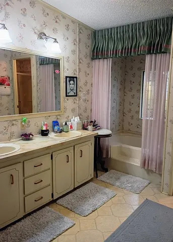a spacious bathroom with a double vanity sink a mirror and a bathtub