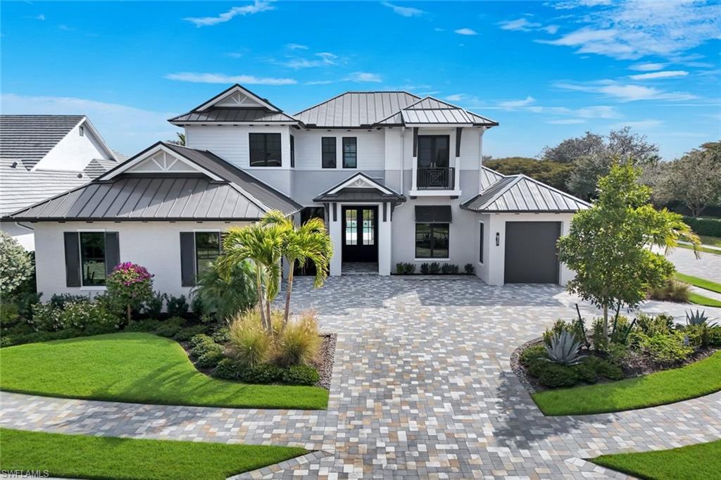 16728 Enclave Circle Naples, FL 34110 - Photo 3 of 49 View of front of home featuring a standing seam roof, an attached garage, a front yard, decorative driveway, and stucco siding