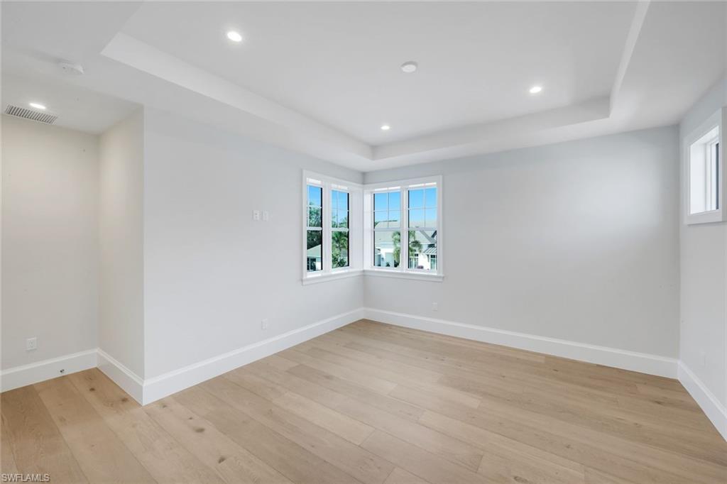 16728 Enclave Circle Naples, FL 34110 - Photo 30 of 49 Spare room with a tray ceiling, plenty of natural light, recessed lighting, and light wood-style floors