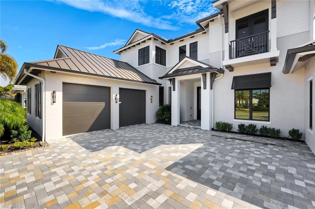 16728 Enclave Circle Naples, FL 34110 - Photo 4 of 49 View of front of house with a standing seam roof, decorative driveway, stucco siding, and a balcony
