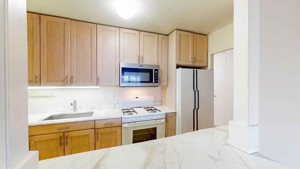 9 Hawthorne Place, Unit 11B Boston, MA 02114 - Photo 4 of 19 a kitchen with granite countertop a sink stainless steel appliances and cabinets