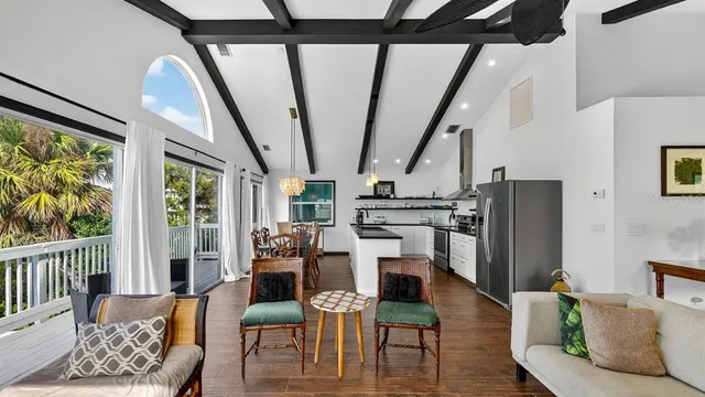 a kitchen with stainless steel appliances granite countertop a dining table chairs refrigerator and wooden floor