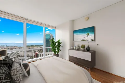 a bedroom with a bed a potted plant on dresser and a wooden floor