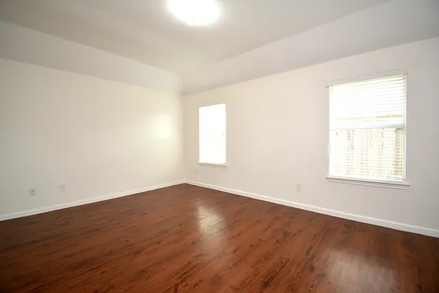an empty room with wooden floor and window