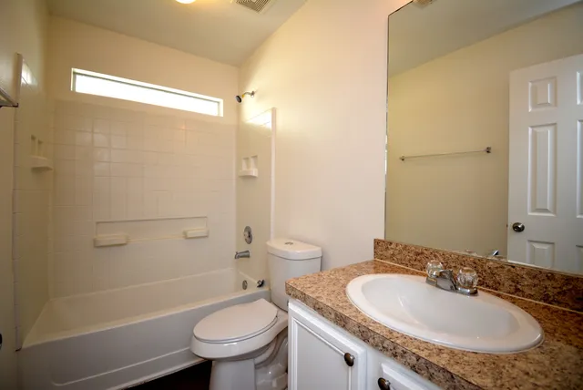 a bathroom with a granite countertop sink a toilet a mirror and shower