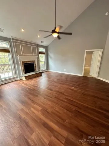 an empty room with wooden floor fireplace and windows