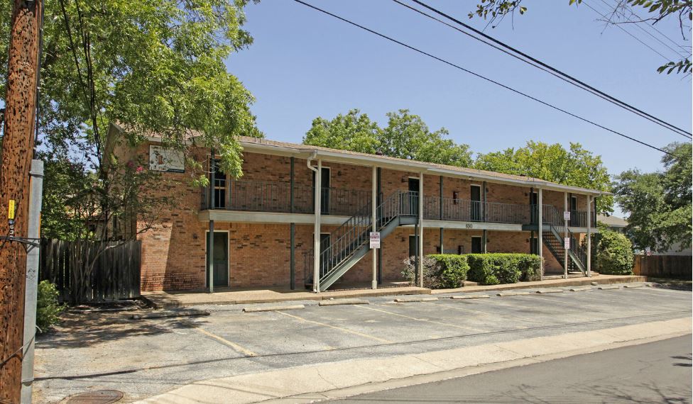 View of building exterior with stairway and uncovered parking