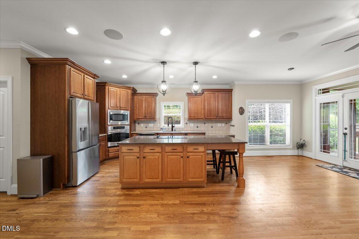 7400 Denlee Road Raleigh, NC 27603 - Photo 13 of 47 a kitchen with stainless steel appliances granite countertop a refrigerator a sink dishwasher a stove and a dining table with wooden floor