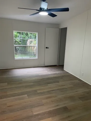 a view of an empty room with wooden floor and a window