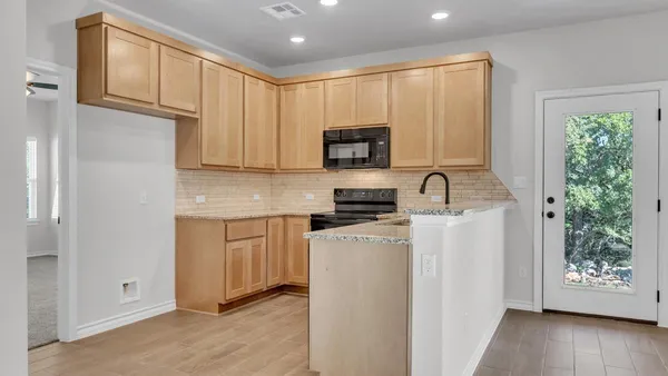 a view of a kitchen with a stove cabinets a ceiling fan and wooden floor