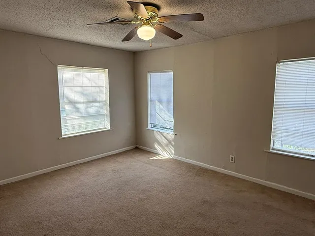 an empty room with windows and fan