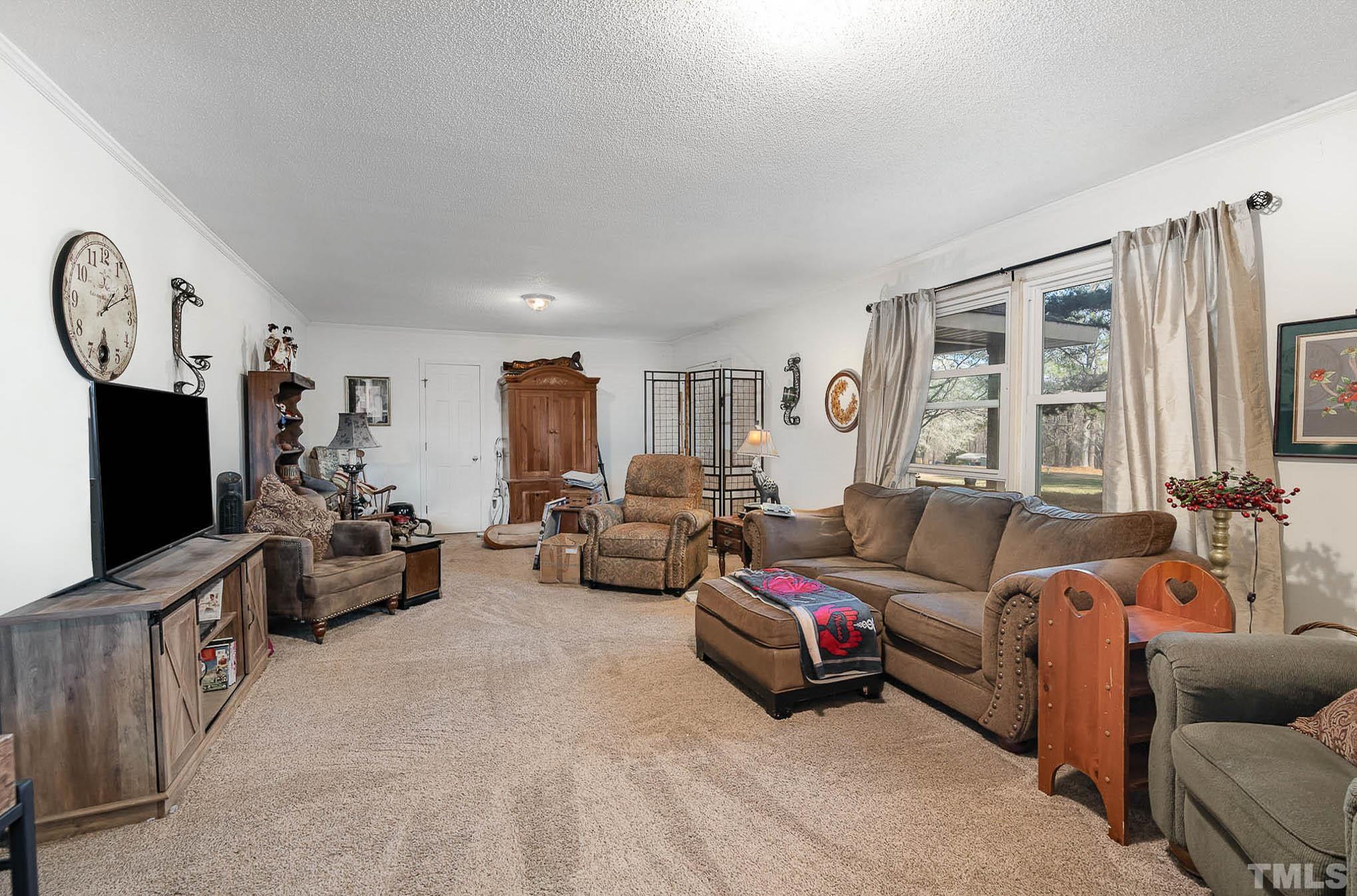 1613 Sanders Road Stem, NC 27581 - Photo 6 of 19 a living room with furniture flat screen tv and a window