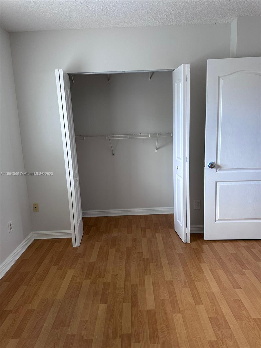 8260 Northwest 10th Street, Unit 7 Miami, FL 33126 - Photo 14 of 23 an empty room with wooden floor and white doors
