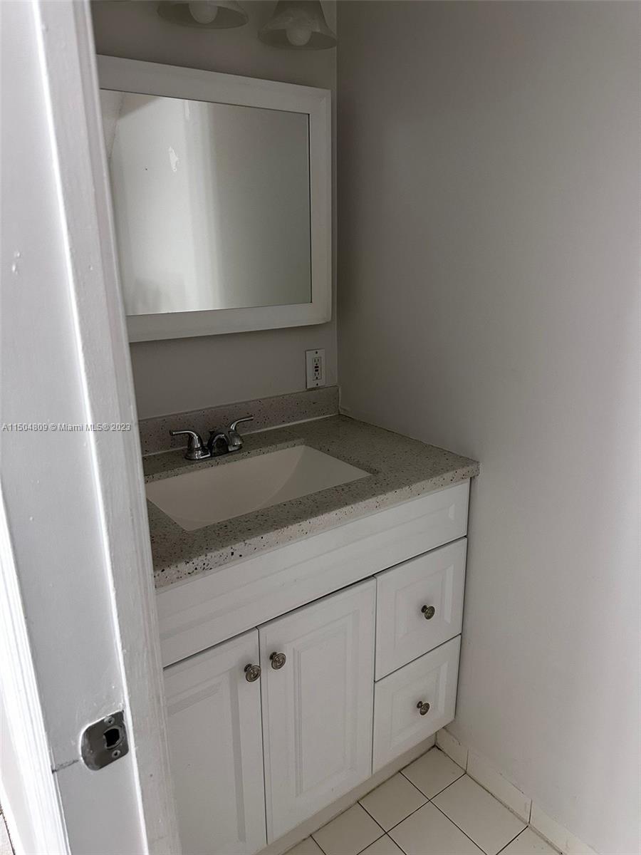 8260 Northwest 10th Street, Unit 7 Miami, FL 33126 - Photo 9 of 23 a bathroom with a granite countertop sink and a mirror