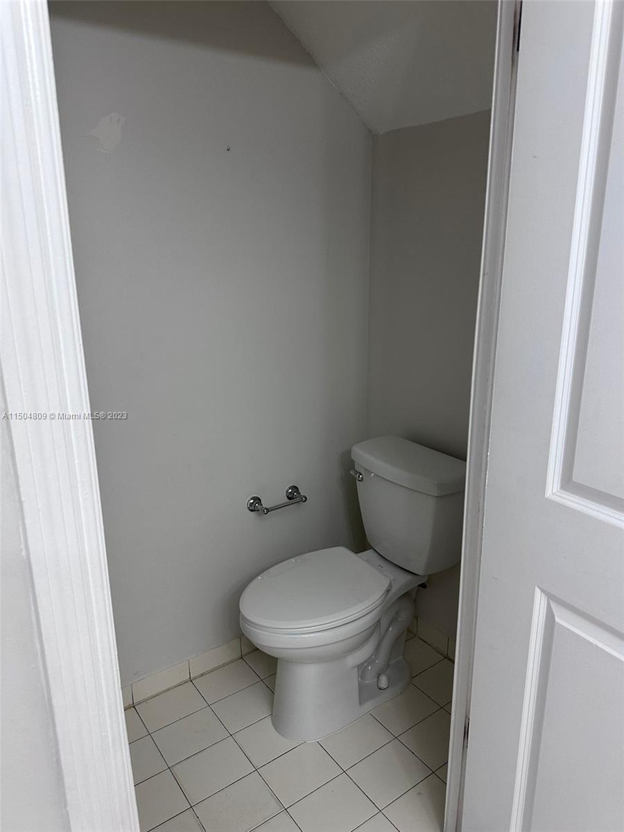 8260 Northwest 10th Street, Unit 7 Miami, FL 33126 - Photo 10 of 23 a white toilet sitting next to a shower curtain