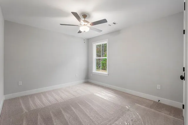 an empty room with a window and a ceiling fan