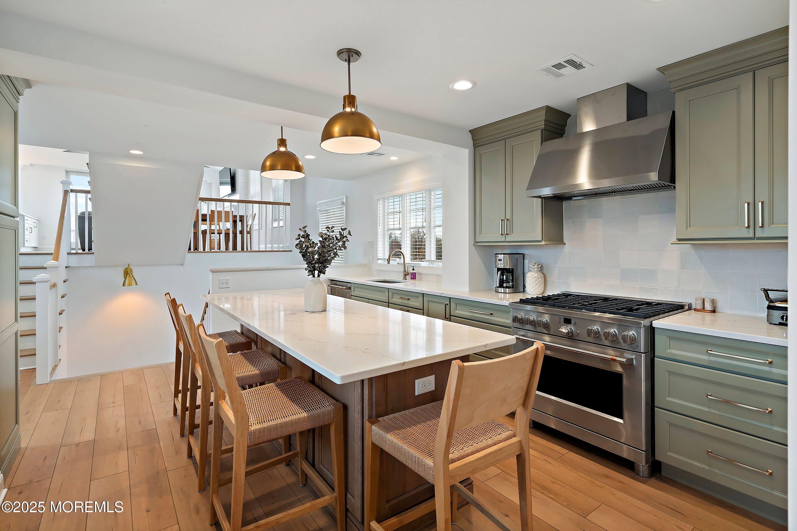 543 Brielle Road Manasquan, NJ 08736 - Photo 9 of 36 a kitchen with stainless steel appliances a stove a sink dishwasher a dining table and chairs with wooden floor