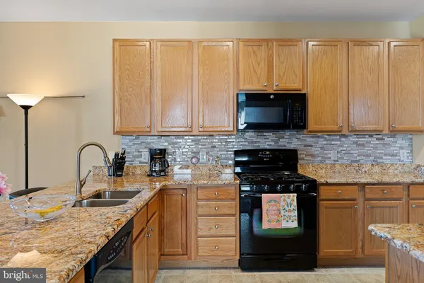 a kitchen with granite countertop a stove top oven microwave and cabinets