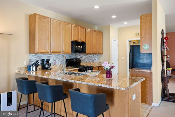 a kitchen with stainless steel appliances granite countertop a stove a sink a microwave a refrigerator and cabinets