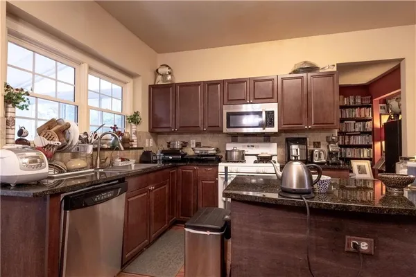 a kitchen with kitchen island granite countertop a sink stove and cabinets
