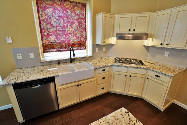 a kitchen with kitchen island granite countertop a sink cabinets and stainless steel appliances