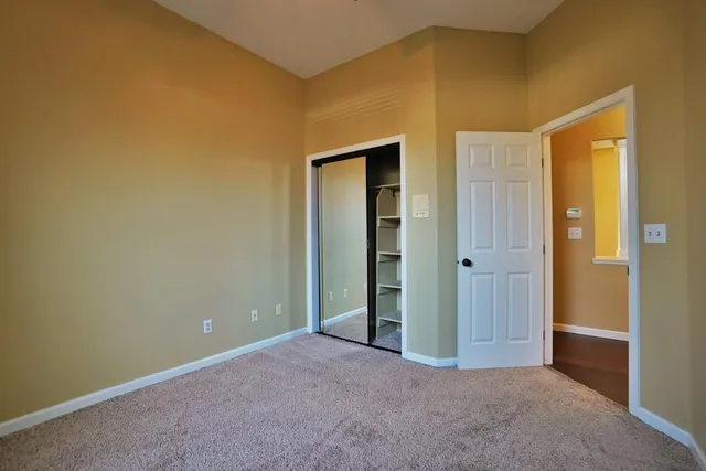 a view of an empty room with a kitchen and a window