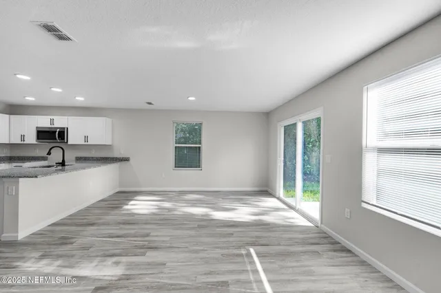 a view of kitchen with granite countertop sink and cabinets
