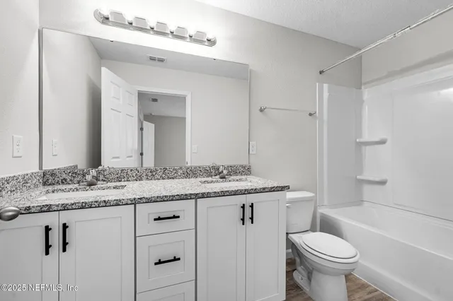 a bathroom with a granite countertop sink toilet mirror and a bathtub
