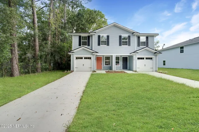a front view of a house with a yard and trees