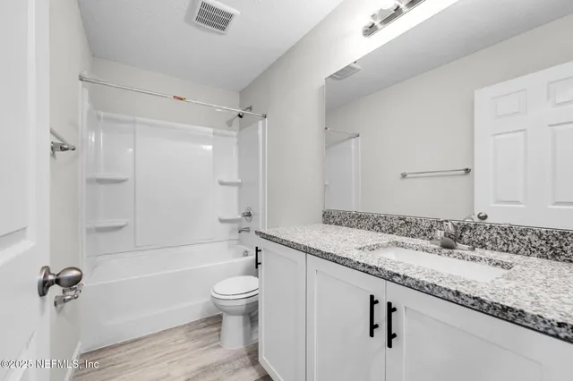 a bathroom with a granite countertop sink a toilet and shower