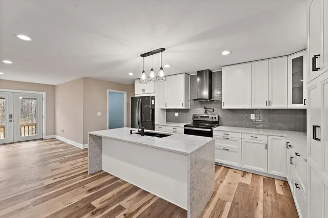 a kitchen with kitchen island granite countertop a sink cabinets and stainless steel appliances