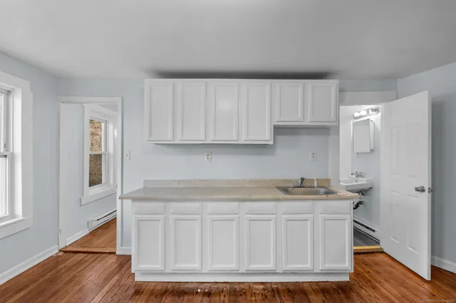 a kitchen with white cabinets and wooden floor