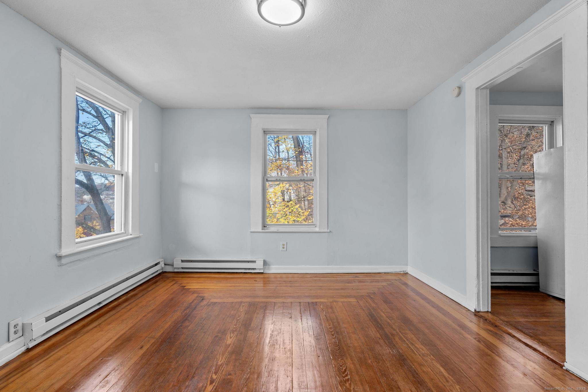 156 Orange Street Waterbury, CT 06704 - Photo 5 of 32 an empty room with wooden floor and windows