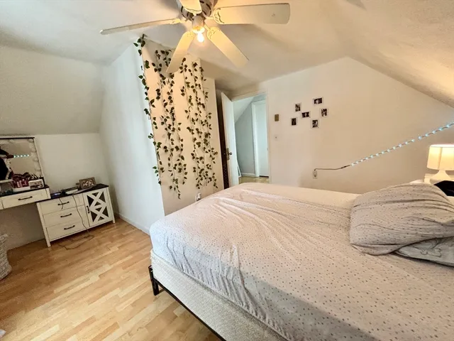 a bedroom with a bed and dresser with wooden floor