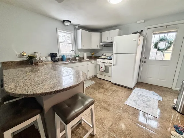 a kitchen with kitchen island granite countertop a sink cabinets and refrigerator