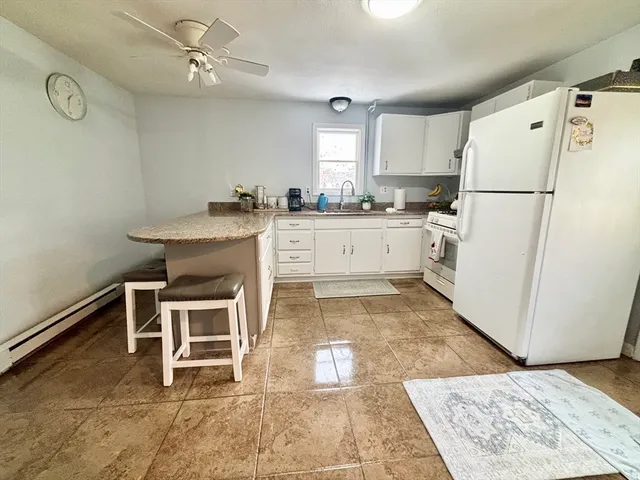 a kitchen with granite countertop a refrigerator a sink and white appliances