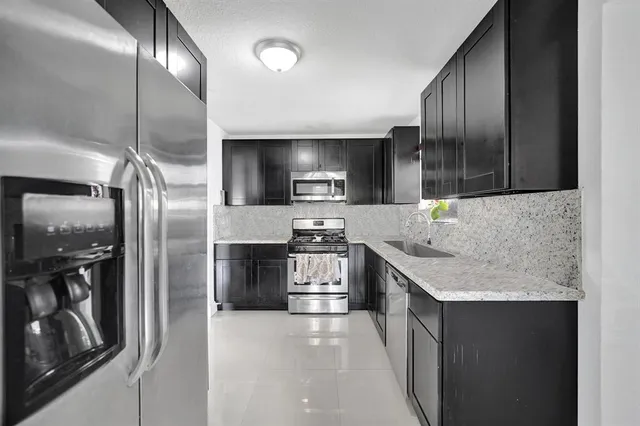 a modern kitchen with stainless steel appliances granite countertop a refrigerator and a stove