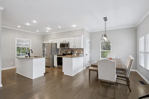 a kitchen with stainless steel appliances kitchen island granite countertop a table chairs and a refrigerator