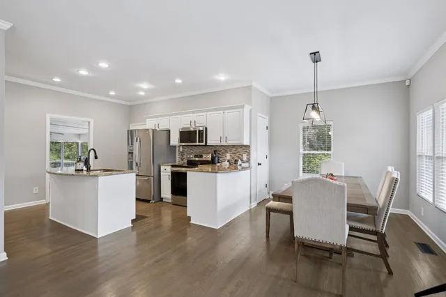 a kitchen with stainless steel appliances kitchen island granite countertop a table chairs and a refrigerator